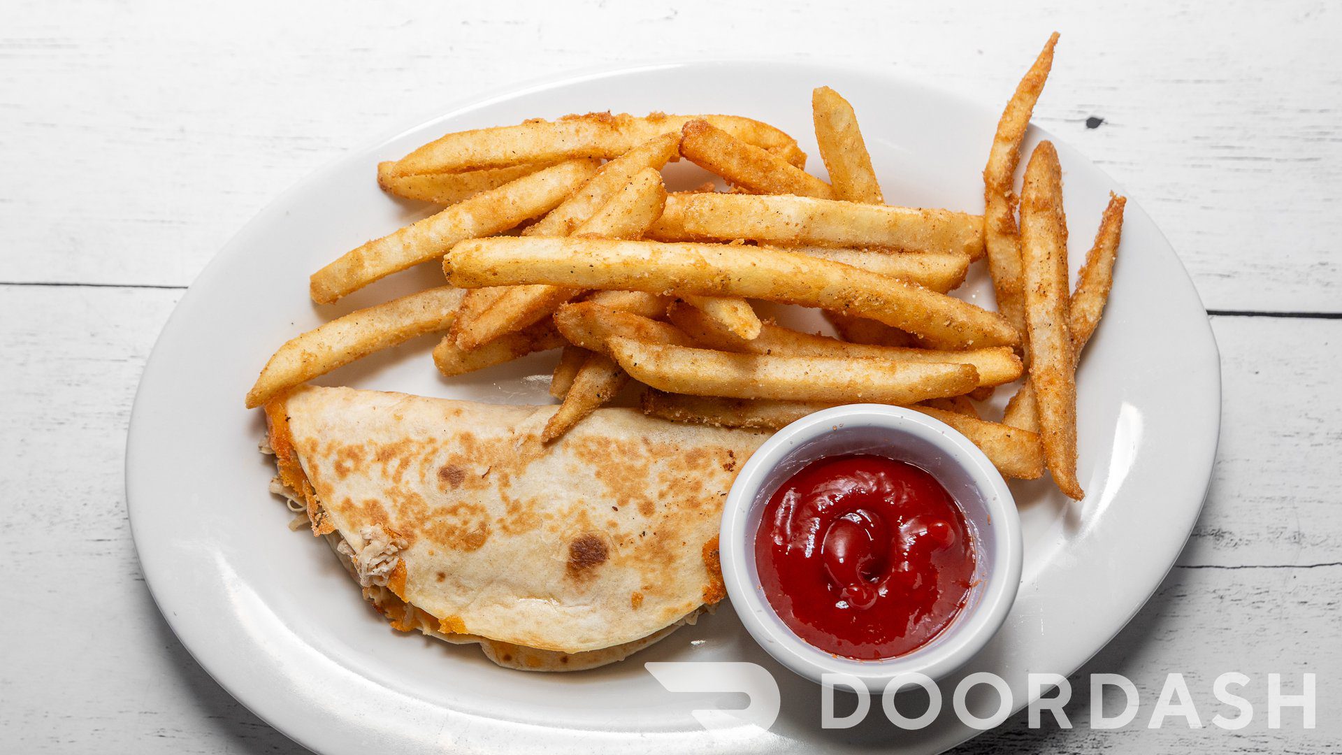 French fries, quesadilla, and ketchup on dish.