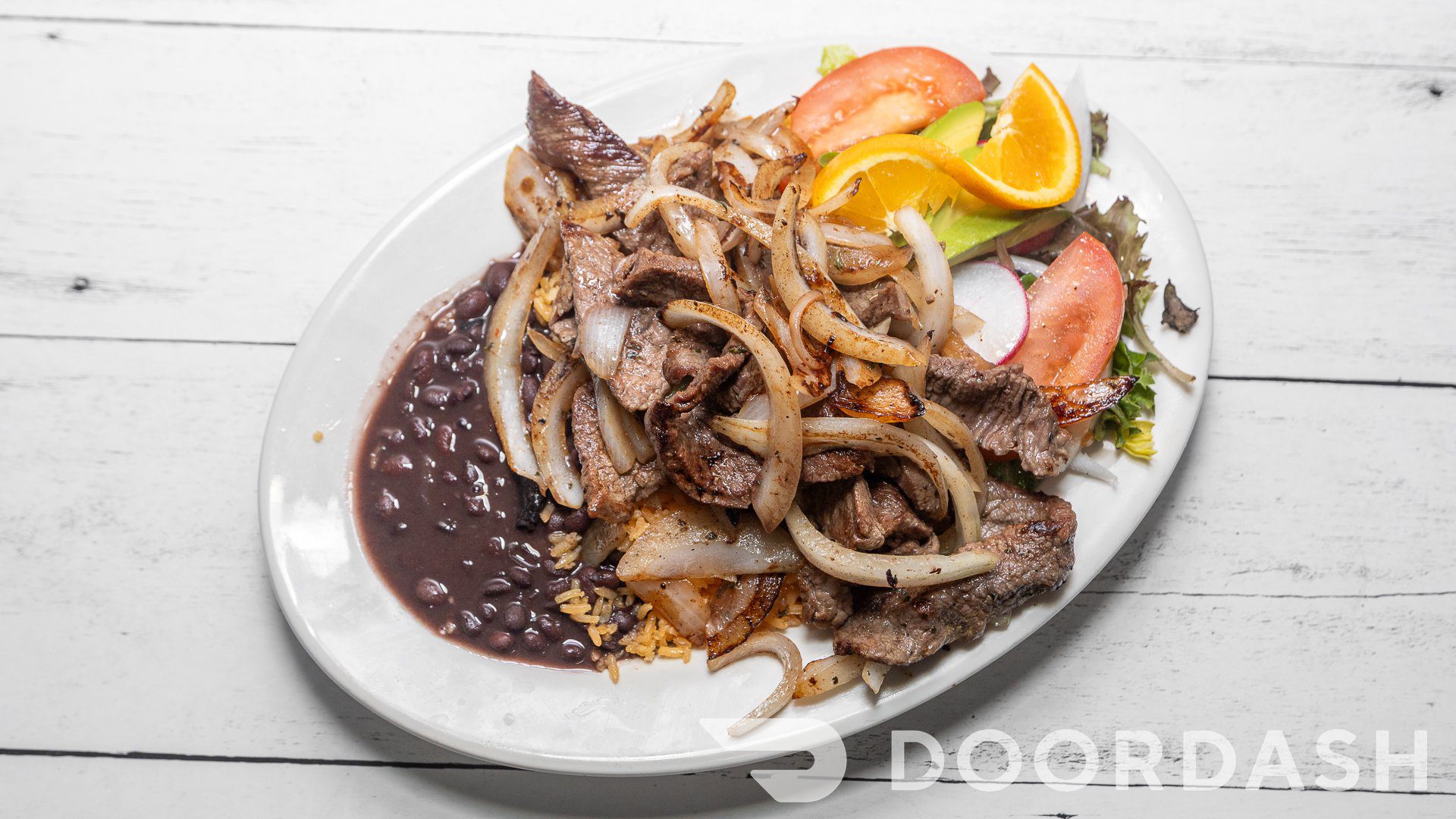 Plate of grilled beef, vegetables, and beans